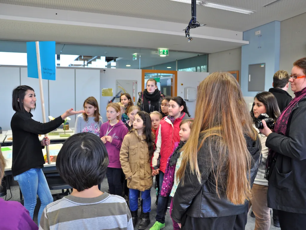 Person führt eine Kindergruppe durch das Gebäude.
